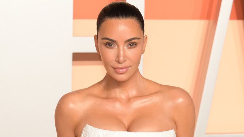 Kim Kardashian sourit dans une robe blanche sans manches