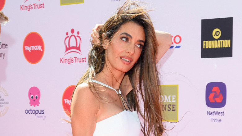 Amal Clooney regarde à droite en robe blanche