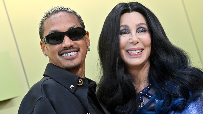 Cher sourit en portant un fard à paupières bleu, à côté d'Alexander Edwards