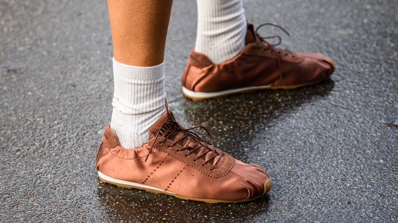 Une personne portant des baskets fines en satin marron