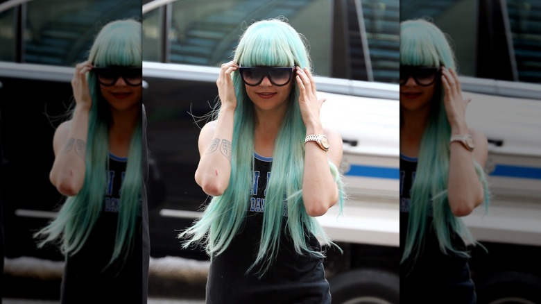 Amanda Bynes marche avec une perruque turquoise et de grandes lunettes de soleil