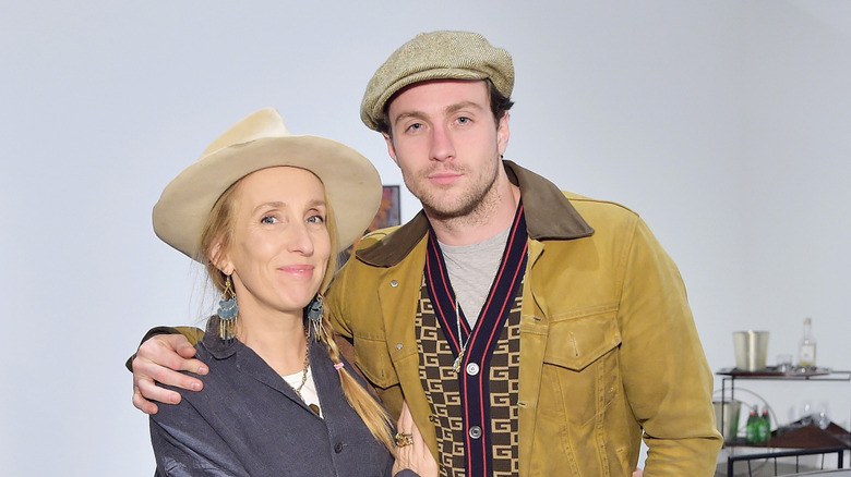 Sam Taylor-Johnson sourit avec un chapeau à côté d'Aaron Taylor-Johnson portant un chapeau