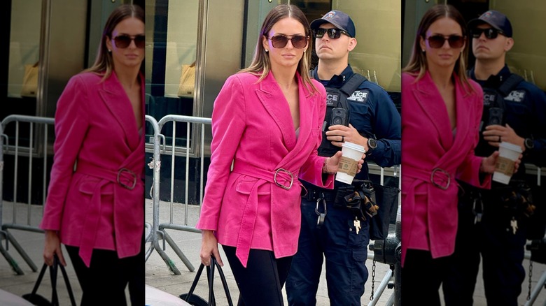 Margo Martin dans un blazer rose se promenant dehors tout en tenant une tasse de café