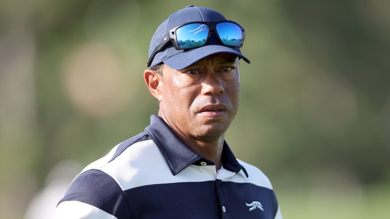 Tiger Woods avec une expression sérieuse et portant une casquette de baseball sur le terrain de golf