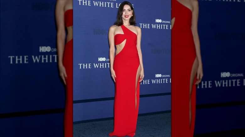 Aubrey Plaza en robe rouge qui fait tourner la tête pour un événement de presse sur le lotus blanc