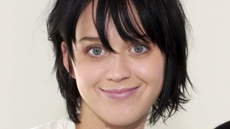 Katy Perry souriante avec des cheveux noirs et un maquillage minimaliste en 2002