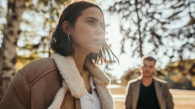 Femme dans le parc ayant l'air stressée avec un homme derrière elle
