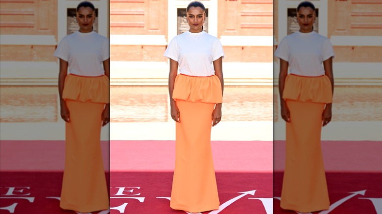 Simone Ashley dans un T-shirt et une jupe à basque orange lors d'un photocall à Londres pour 