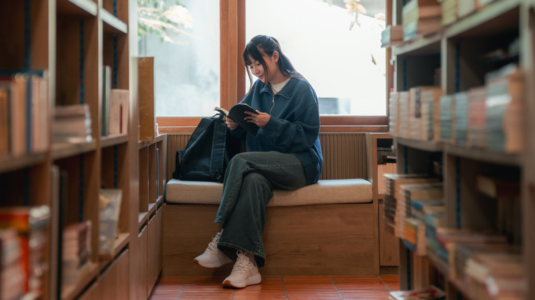 Femme avec une pile de petits livres sur la tête
