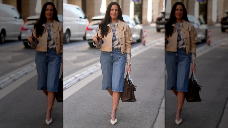 Une femme marchant dans la rue en short en jean long et une veste beige