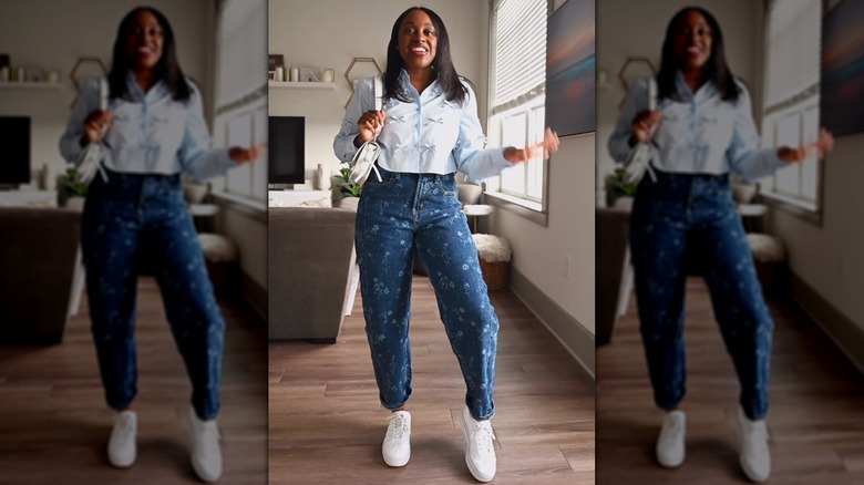 Une femme vêtue d'une chemise courte et d'un jean fleuri avec des baskets blanches