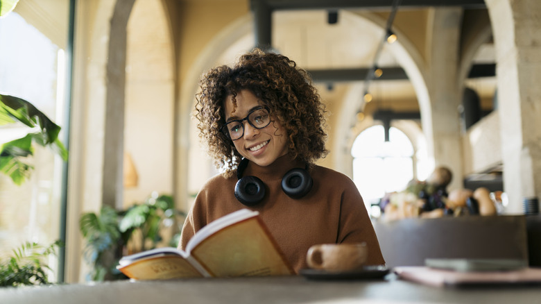Jeune femme appréciant un livre et un café dans un café