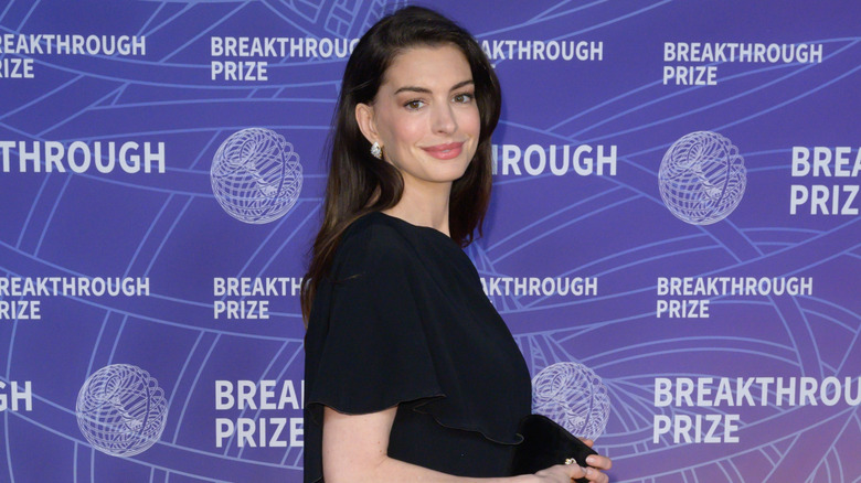 Anne Hathaway sur le tapis rouge, regardant par-dessus son épaule