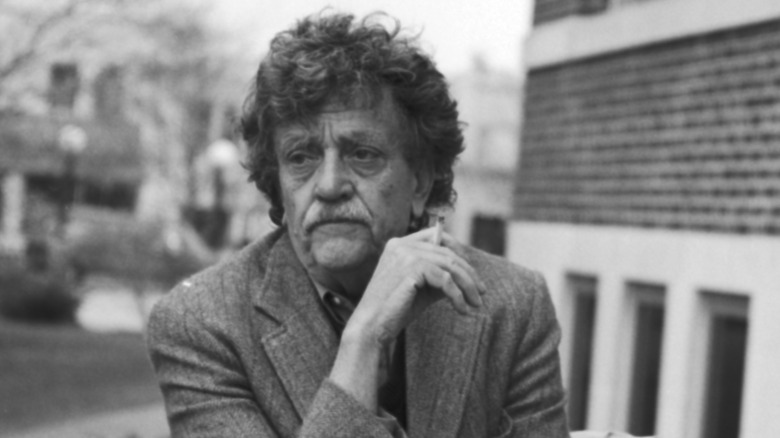Une photo en noir et blanc de Kurt Vonnegut Jr. fumant une cigarette dehors