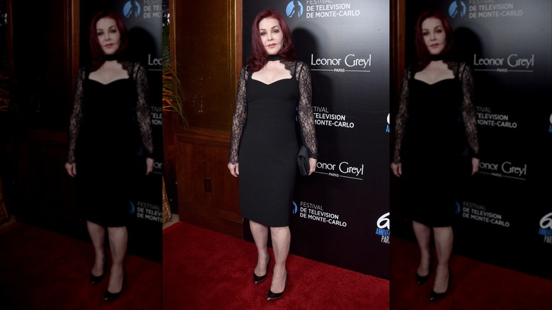 Priscilla Presley portant une robe noire avec des manches en dentelle lors d'un événement sur le tapis rouge