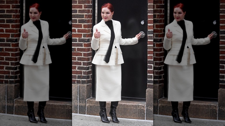 Priscilla Presley lève le pouce en portant un tailleur-jupe blanc