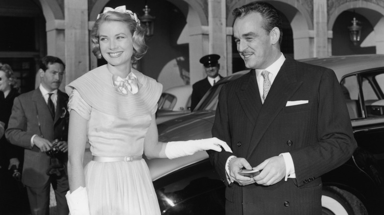 Grace Kelly avec sa main sur le bras du Prince Rainier III devant la voiture
