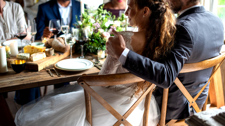 Jeunes mariés s'embrassant à table rustique