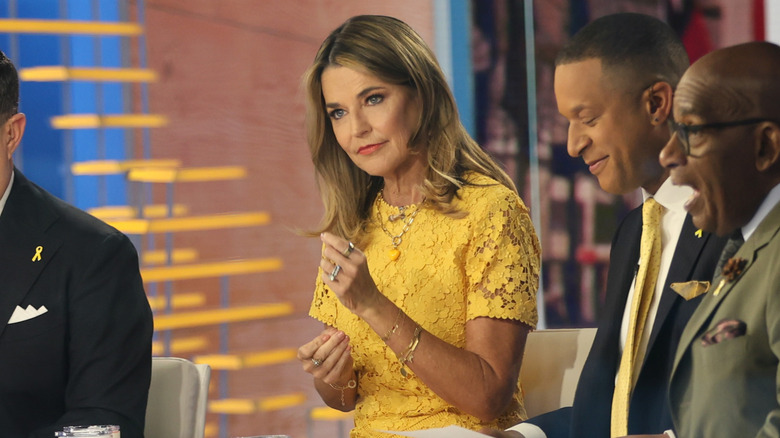 Savannah Guthrie est assise avec un visage impassible, vêtue d'une robe jaune