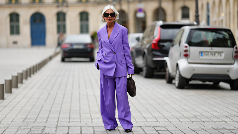 Une femme plus âgée debout dans la rue dans un costume violet