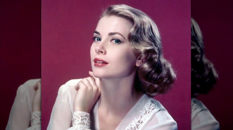 Grace Kelly posant devant un fond marron portant une blouse blanche