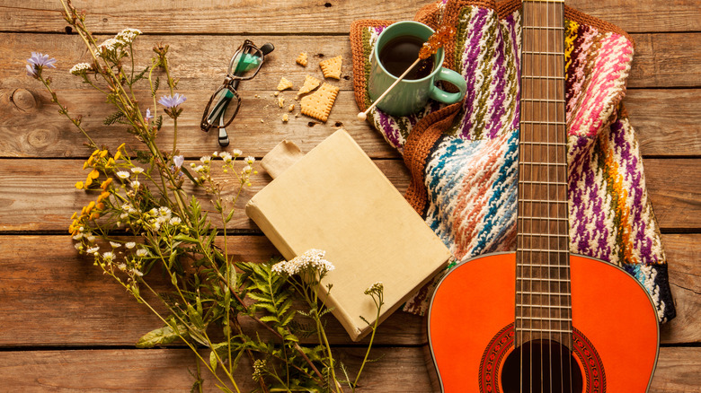 Livre entouré de fleurs, d'une guitare et d'une tasse à café