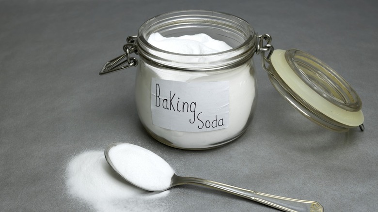 Un pot de bicarbonate de soude à côté d'une cuillère débordant de bicarbonate de soude