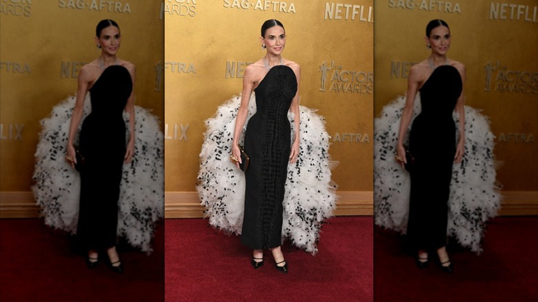 Demi Moore sur le tapis rouge dans une robe noire avec une grande agitation blanche