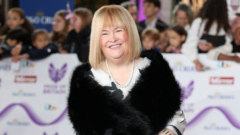 Susan Boyle souriante sur le tapis rouge en 2025 avec un carré blond