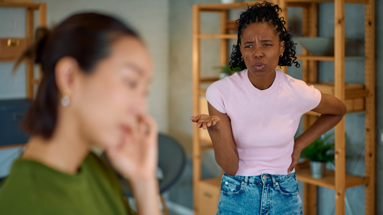 couple confronté à une dispute à la maison, un partenaire exprimant sa frustration tandis que l'autre détourne le regard, soulignant les problèmes de communication et les conflits dans leur relation
