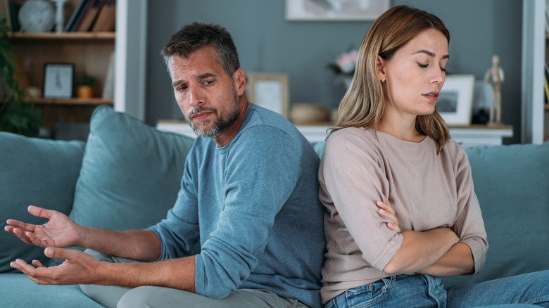 Plan d'un jeune couple en désaccord à la maison. Couple s'ignorant alors qu'il était assis dos à dos sur le canapé.