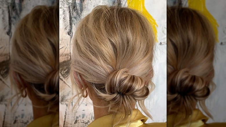 Une femme aux cheveux blonds coiffés d’un chignon bas et en désordre