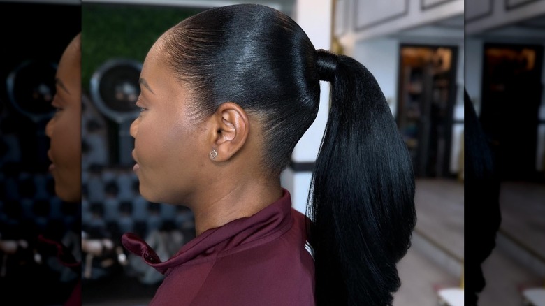 Une femme aux cheveux noirs attachée en queue de cheval lissée