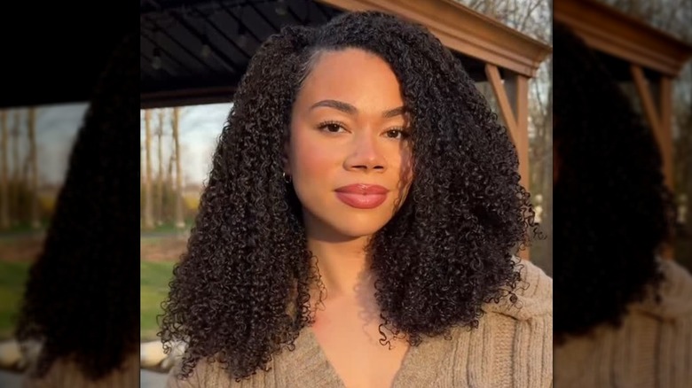 Une femme aux cheveux bouclés dans une partie latérale profonde