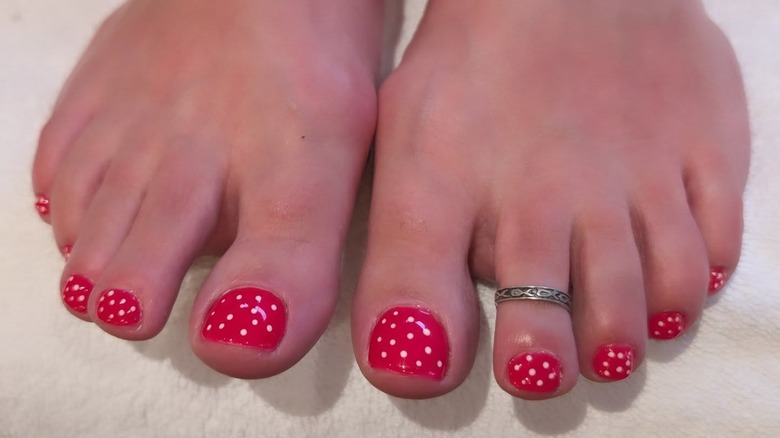 Les pieds d'une personne avec une pédicure à pois rouges et blancs