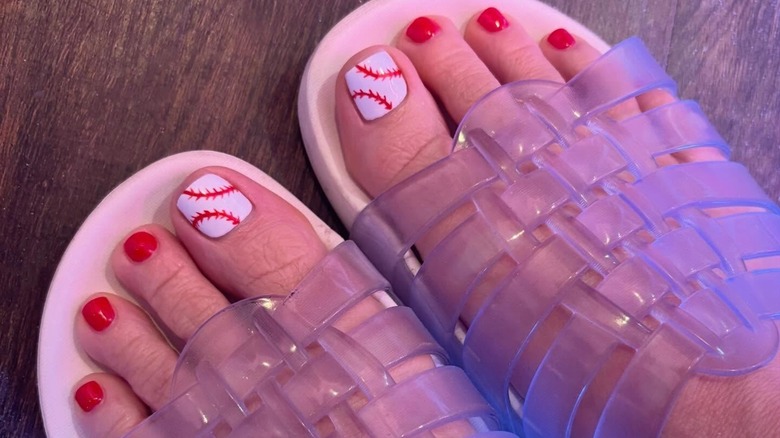 Les pieds d'une femme avec une manucure inspirée du baseball