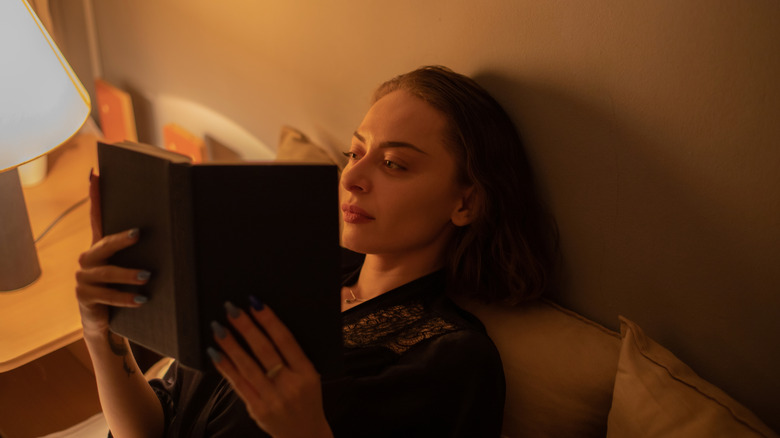 Une femme s'enveloppe dans une couverture et lit un livre