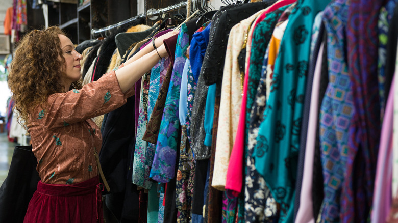 Femme faisant du shopping pour des robes dans une friperie