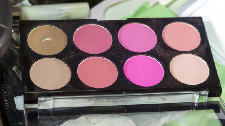Une palette de maquillage noire contenant plusieurs nuances de blush