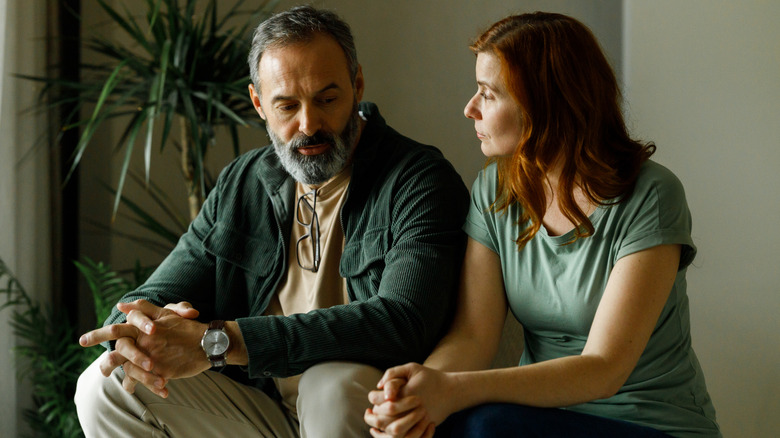 Homme et femme assis l'un à côté de l'autre, l'air triste