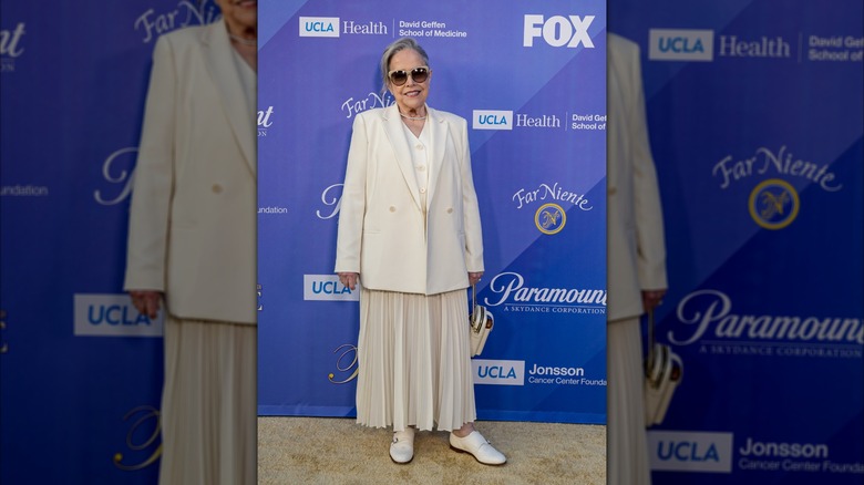 Kathy Bates portant un costume entièrement blanc et des lunettes de soleil beiges