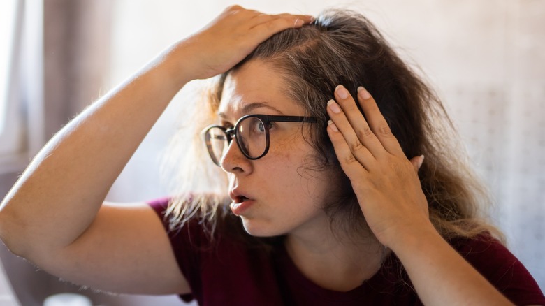Une femme soulevant ses cheveux pour voir ses mèches grises