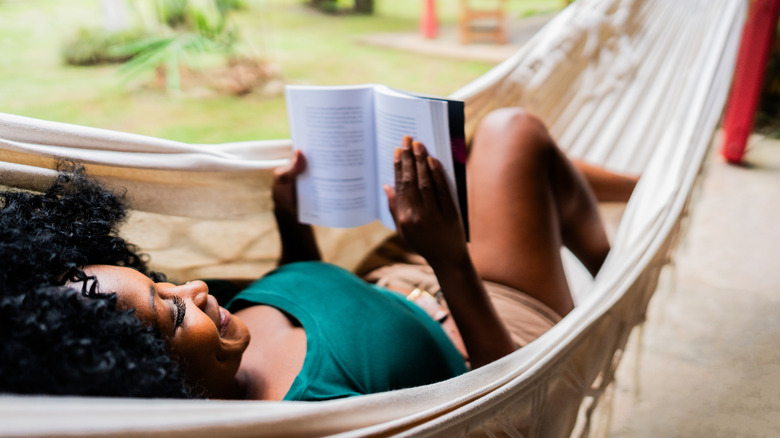 Femme lisant un livre sur un hamac à l'extérieur