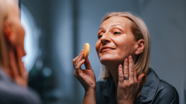 Femme plus âgée, se maquiller avec une éponge