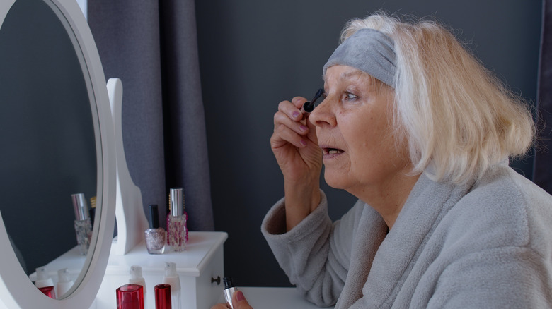 Femme plus âgée appliquant du mascara