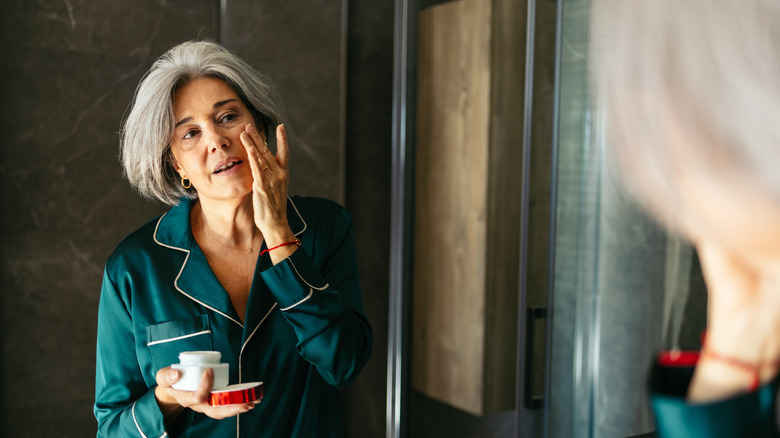 Femme plus âgée appliquant une crème pour le visage
