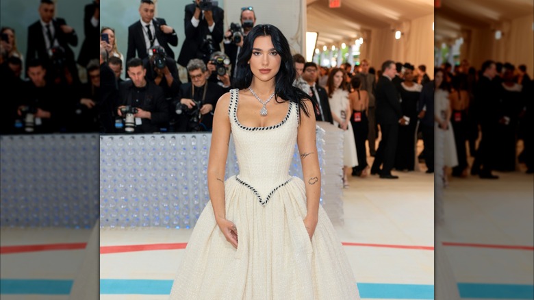 Dua Lipa portant une robe de mariée blanche et un grand collier de diamants