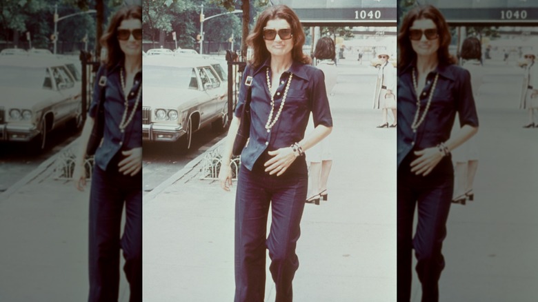 Jackie Kennedy dans un long collier de perles avec une chemise bleu marine et un pantalon bleu marine