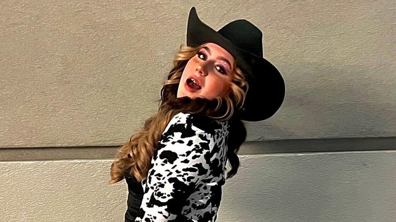 Bailee Ann DeFord posant avec un chapeau de cowboy noir et une veste à imprimé vache en 2026