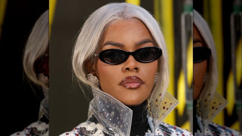 Teyana Taylor posant avec des cheveux gris lors d'un défilé Chanel pendant la Fashion Week de Paris tout en portant des lunettes de soleil foncées